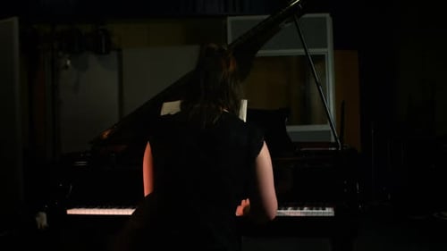 Woman Plays Piano in Recording Studio at Night