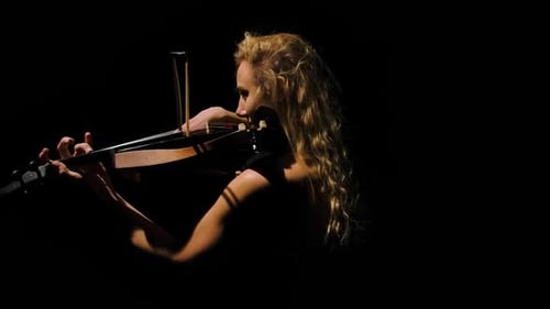 Side View of an Attractive Young Woman Playing the Violin in the Dark