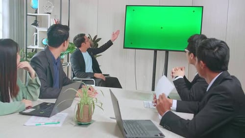 Young Asian Businessman Presentation To His Business Colleagues, Pointing At Tv Mock Up Green Screen