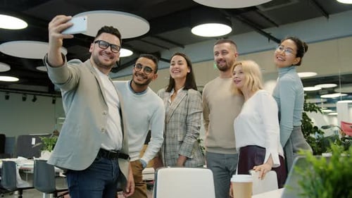 Multi-racial Group of Coworkers Taking Selfie in Office Room Using Smartphone