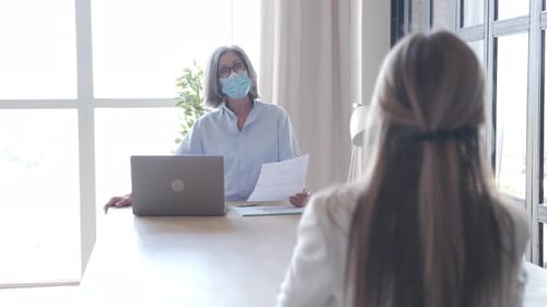 Woman Interviewing Candidate in Office Wearing Mask