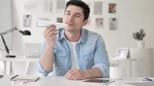Young Adult Man Plays with Paper Airplane