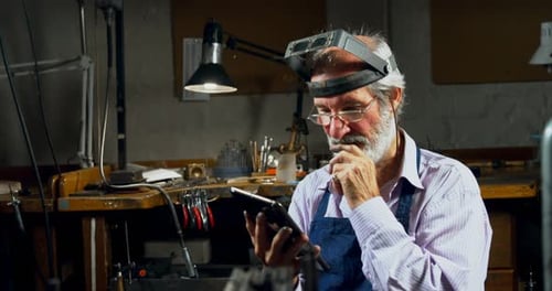 Goldsmith using digital tablet in workshop