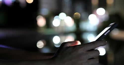 Working on mobile phone in city at night
