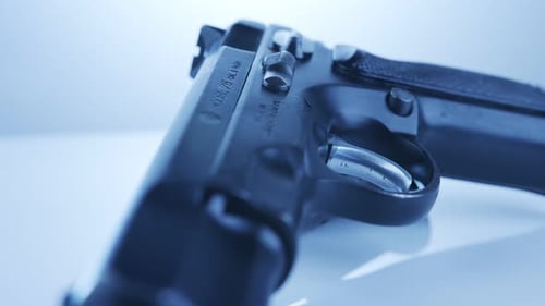 Gun Control. 9mm handgun with bullets rotating on a reflective surface