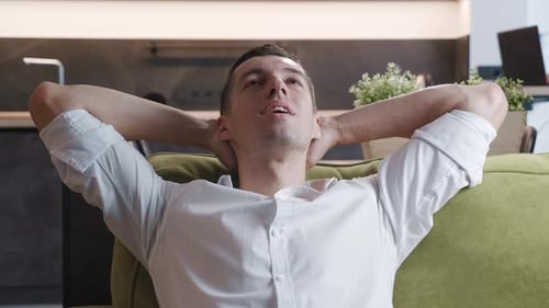 Calm Relaxed Young Man Resting on Cozy Sofa at Home. Happy Businessman Breathing Fresh Air Lounge on
