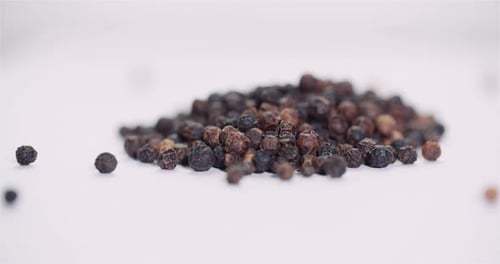 Pile of Whole Black Peppercorns on White