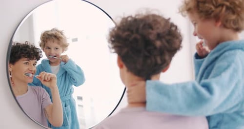Woman and Child Brushing Teeth Together in Mirror