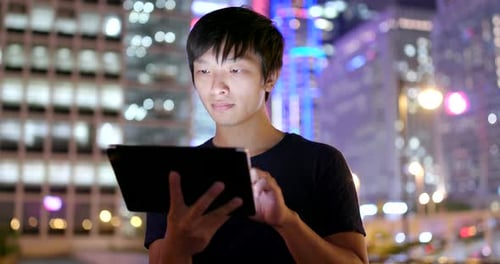 Young Adult Uses Tablet Computer at Night