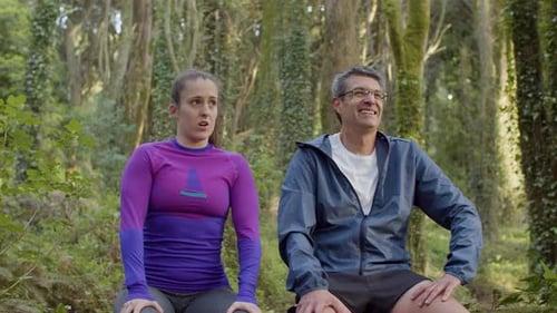 Man and Woman Sitting and Resting After Trail Running in Forest