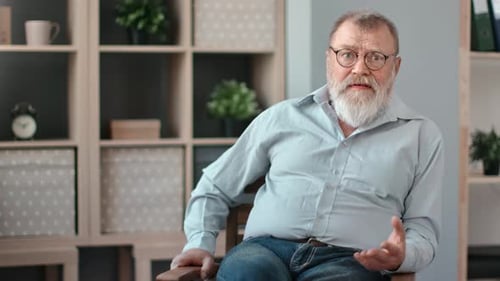 Man With White Beard Sits and Gestures