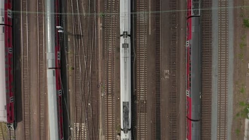 Vue aérienne de haut en bas d'un train de voyageurs sur une voie à voies multiples avec lignes à haute tension et autres