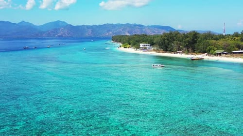 Calm clear water of turquoise lagoon over rocky sea bottom, boats floating near shore of tropical is