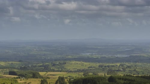 Time lapse of distant rural agriculture landscape of fields with passing clouds on a sunny summer da