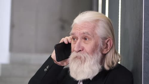 Reifer Mann im Anzug telefoniert im Büro