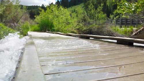 Rushing river water is seen over flowing on top of a bridge. (slow motion)