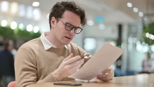 Concerned Man Reading Documents at Workplace Table