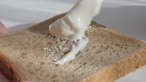 Spreading Creamy Topping on a Slice of Bread