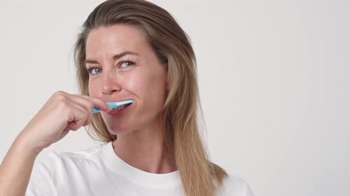 Woman Brushing Her Teeth, Smiling on White Background