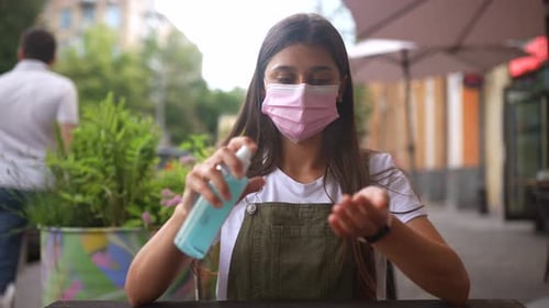 Jovem mulher pulverizando antisséptico para as mãos durante a quarentena de perto