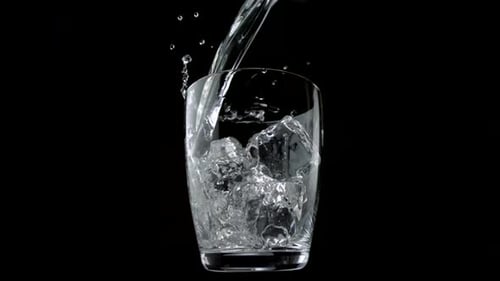 Pouring water into glass with ice cubes, Slow Motion