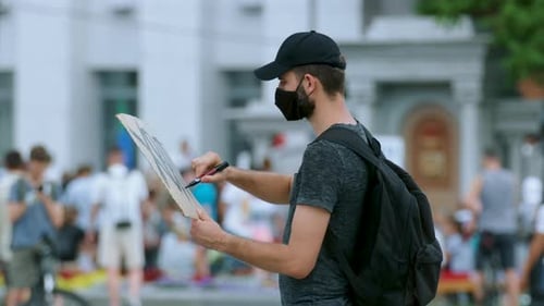 Man Writes on Sign in Crowd and Raises It
