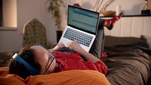 Person Lying on Bed Typing on Laptop