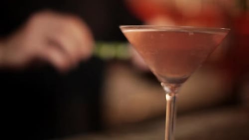 Barkeeper garniert Cosmopolitan mit Limettenschale