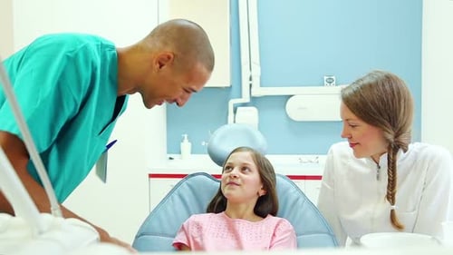 Friendly dentist and her assistant talking with lovely little girl