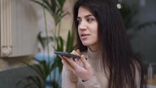 Portrait of Confident Woman Recording Voice Mail on Smartphone Sitting in Cafe