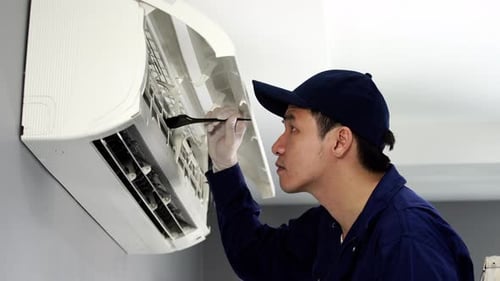 technician service using brush to cleaning the air conditioner indoors