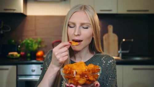 Woman Eats Potato Chips in Her Kitchen