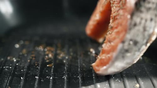 A Salmon Fillets is Turning Over on the Grill Pan with Tongs
