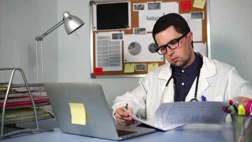Doctor Reviews Documents at His Desk