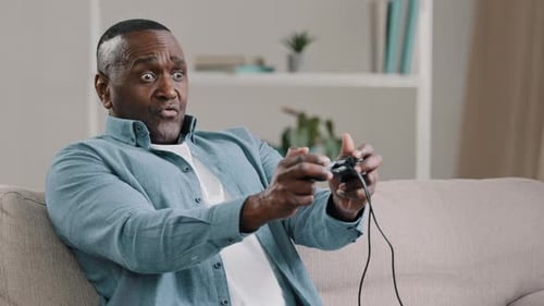 Man Playing Video Game on Couch, Focused Expression
