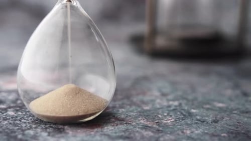 Hourglass on Table Sand Flowing Through the Bulb of Sandglass