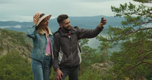 A Woman and a Man are Standing on Top of a Cliff and Looking at Nature