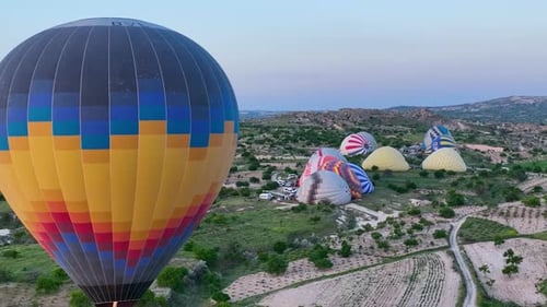 Hot air balloons fly over the mountainous landscape of Cappadocia, Turkey.