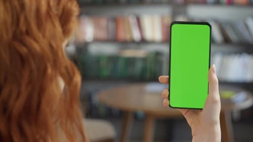 Back View of Young Woman at Home Office Sitting on Library Collage With Green Mockup Screen