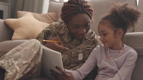 Military Woman Drawing With Her Daughter At Home