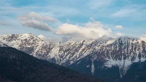 Panning to the right. Clouds above mountains covered with snow.