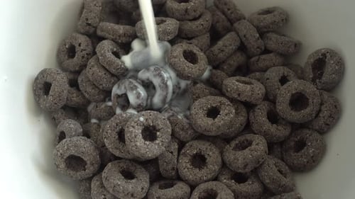 Pouring Milk over Chocolate Cereal in Bowl