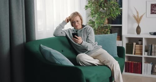 Woman Relaxing on Couch Using Smartphone