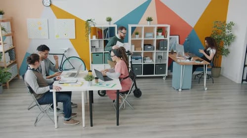 Business Team Working in Creative Office While Guy Riding Scooter Indoors Having Fun