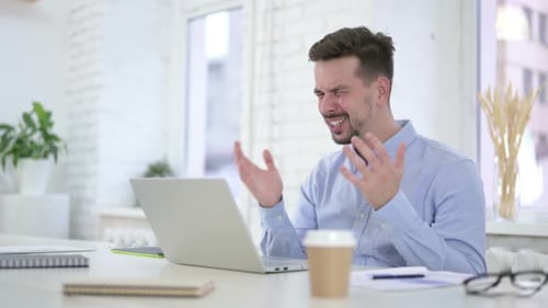 Schockierter Mann reagiert auf Verlust am Desktop, erstaunt