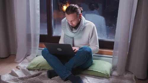 Man Working on Laptop by Rainy Window at Night