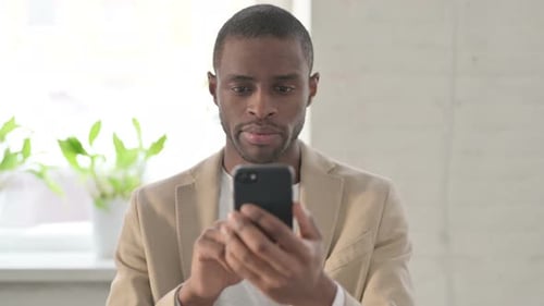 Young Adult Using Smartphone Smiling Indoors