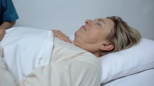 Femme malade souffrant de fièvre et de délires, infirmière mettant une compresse sur le front