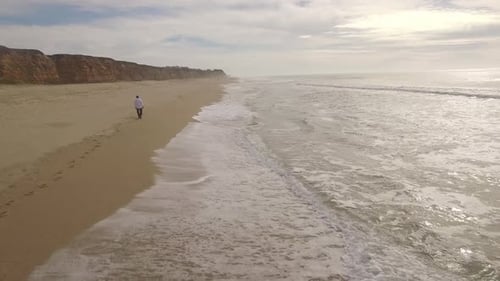 Aerial View of Beach as Man Walks Near Ocean
