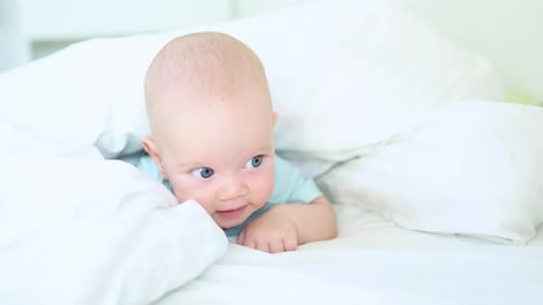 Adorable Baby Lying on White Bed in Bright Room